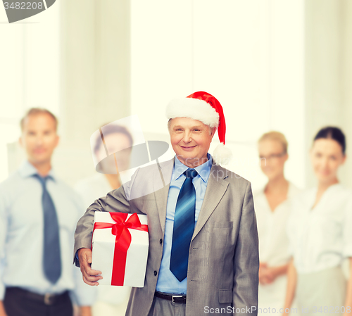 Image of smiling man in suit and santa helper hat with gift