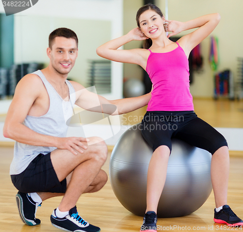 Image of male trainer with woman doing crunches on the ball
