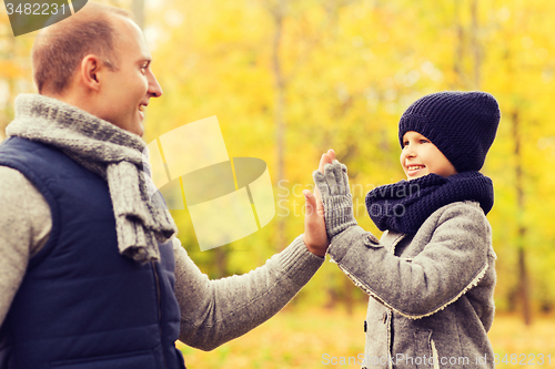 Image of happy father and son making high five in park