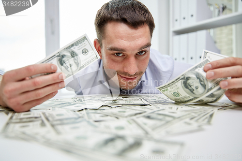 Image of happy businessman with heap of money in office