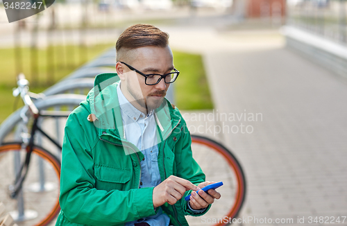 Image of young hipster man with smartphone and byke
