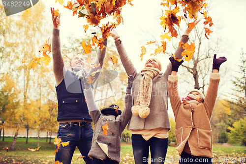 Image of happy family playing with autumn leaves in park