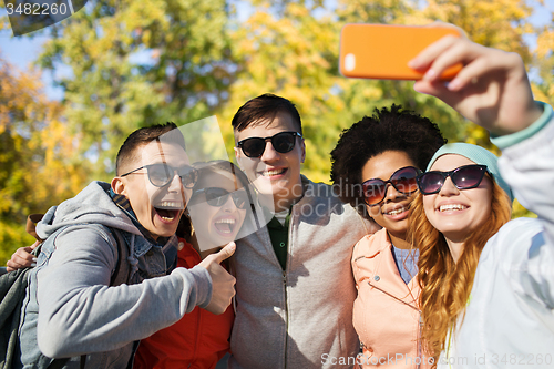 Image of smiling friends taking selfie with smartphone