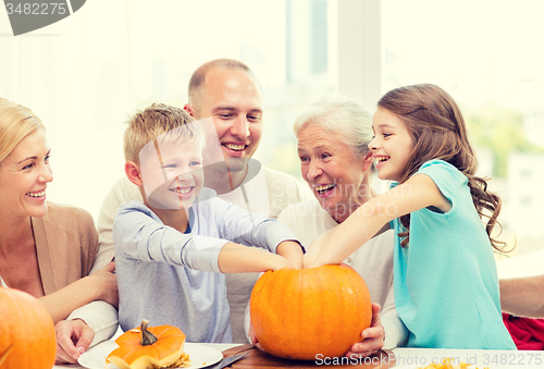 Image of happy family sitting with pumpkins at home