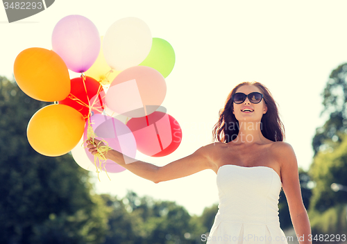 Image of smiling young woman in sunglasses with balloons