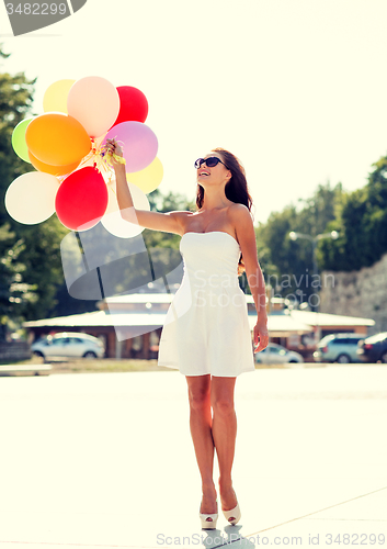 Image of smiling young woman in sunglasses with balloons