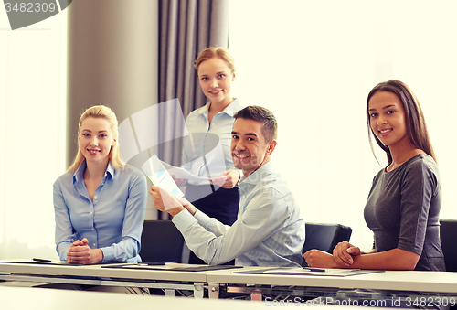 Image of smiling business people with papers in office