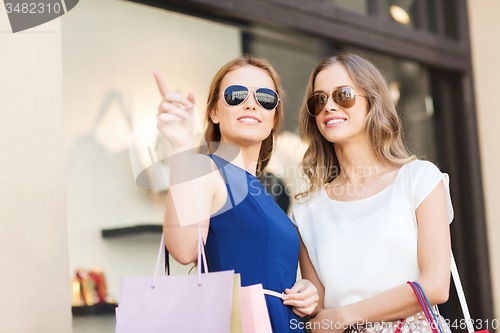 Image of happy young women with shopping bags in mall