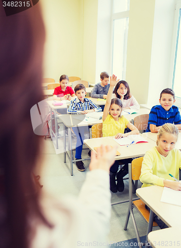 Image of group of school kids raising hands in classroom