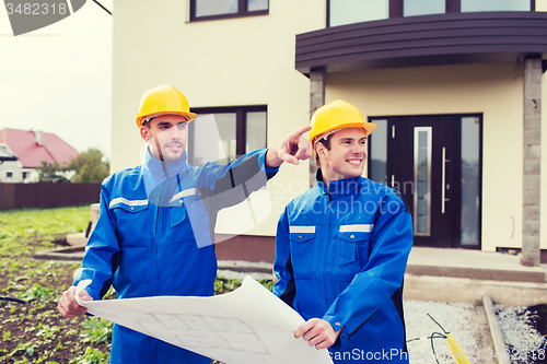 Image of smiling builders with blueprint pointing finger