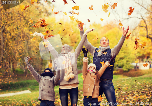 Image of happy family playing with autumn leaves in park