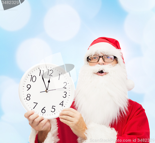 Image of man in costume of santa claus with clock