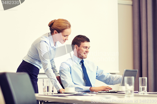 Image of businessman and secretary with laptop in office