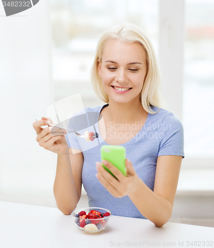Image of woman with smartphone eating fruits at home