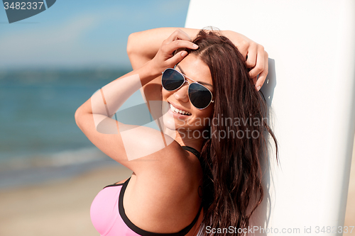 Image of smiling young woman with surfboard on beach