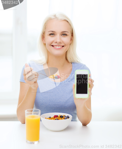 Image of smiling woman with smartphone eating  breakfast 