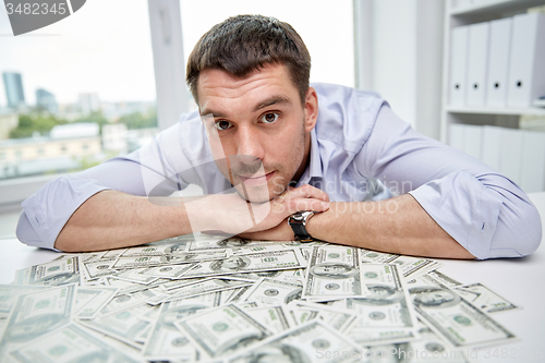 Image of happy businessman with heap of money in office