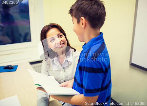 Image of school boy with notebook and teacher in classroom