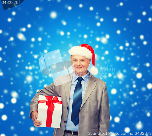 Image of smiling man in suit and santa helper hat with gift