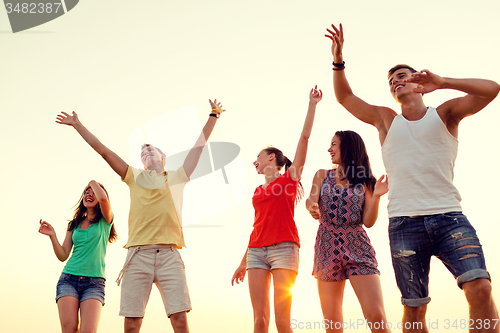 Image of smiling friends dancing on summer beach