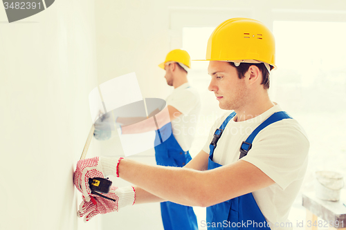 Image of group of builders with measuring tape indoors