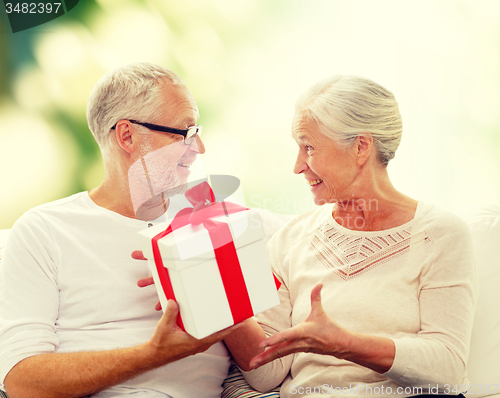 Image of happy senior couple with gift box at home