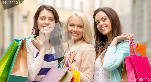 Image of three smiling girls with shopping bags in ctiy