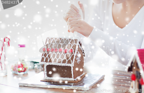 Image of close up of woman making gingerbread house at home