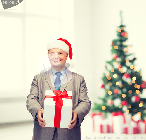 Image of smiling man in suit and santa helper hat with gift