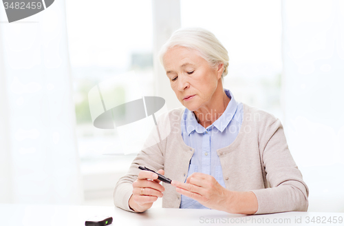 Image of senior woman with glucometer checking blood sugar