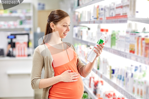 Image of happy pregnant woman choosing lotion at pharmacy