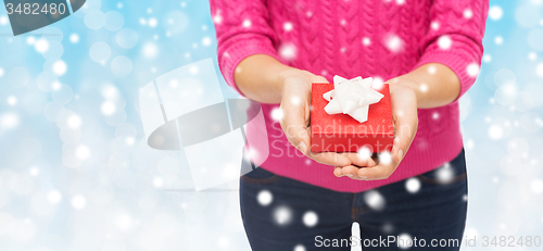 Image of close up of woman in pink sweater holding gift box