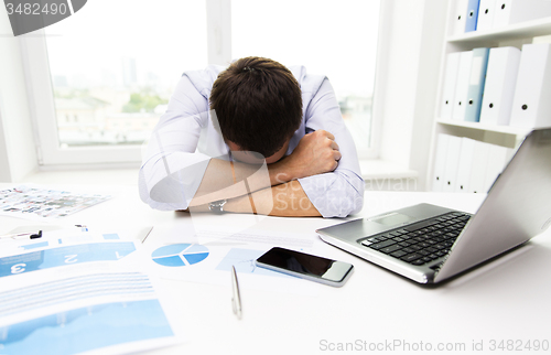 Image of businessman with laptop and papers in office