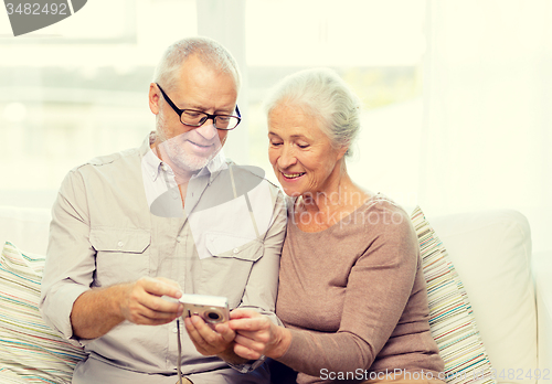 Image of happy senior couple with camera at home