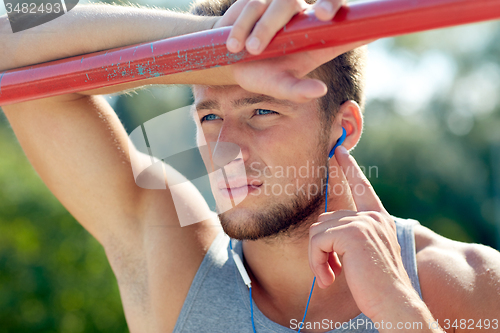 Image of young man with earphones and horizontal bar