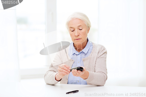 Image of senior woman with glucometer checking blood sugar