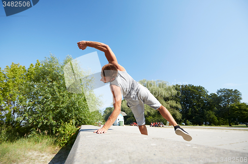 Image of sporty young man jumping in summer park