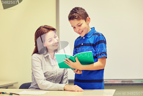 Image of school boy with notebook and teacher in classroom