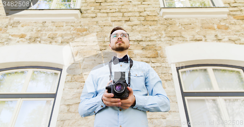 Image of happy young hipster man with film camera in city