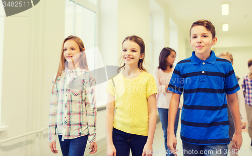 Image of group of smiling school kids walking in corridor