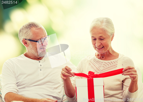 Image of happy senior couple with gift box at home