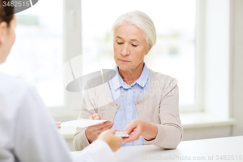 Image of doctor giving prescription and drug to woman 
