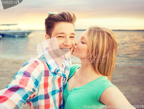 Image of happy couple taking selfie on summer beach