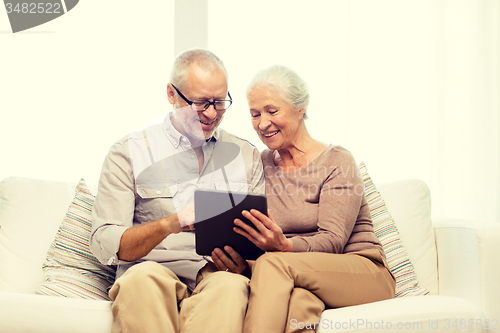 Image of happy senior couple with tablet pc at home
