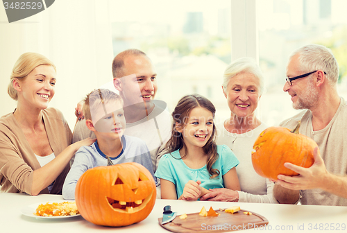 Image of happy family sitting with pumpkins at home