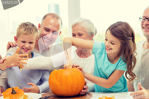 Image of happy family sitting with pumpkins at home