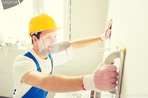 Image of smiling builder with grinding tool indoors