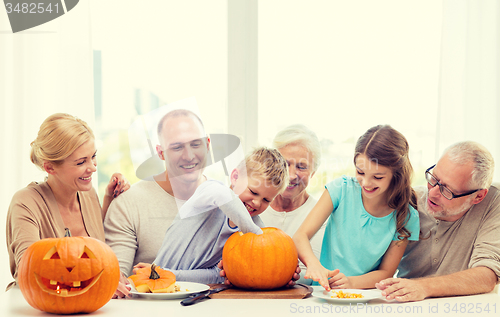 Image of happy family sitting with pumpkins at home