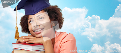 Image of happy african bachelor girl with books over sky