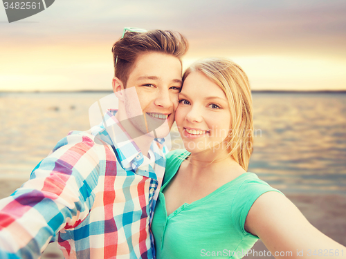 Image of smiling couple with smartphone on summer beach